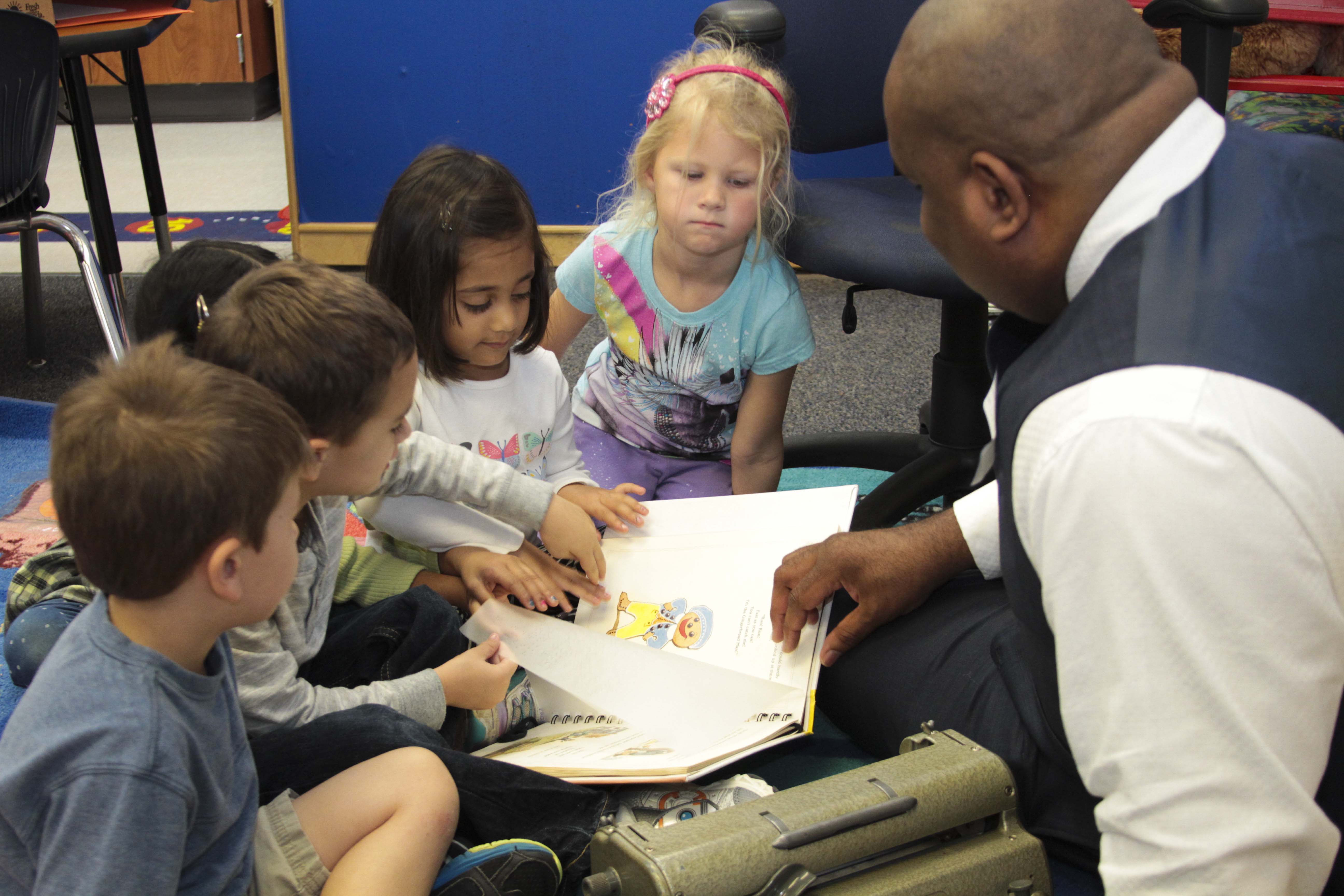 Walter Blackmon with kids and a Braille book